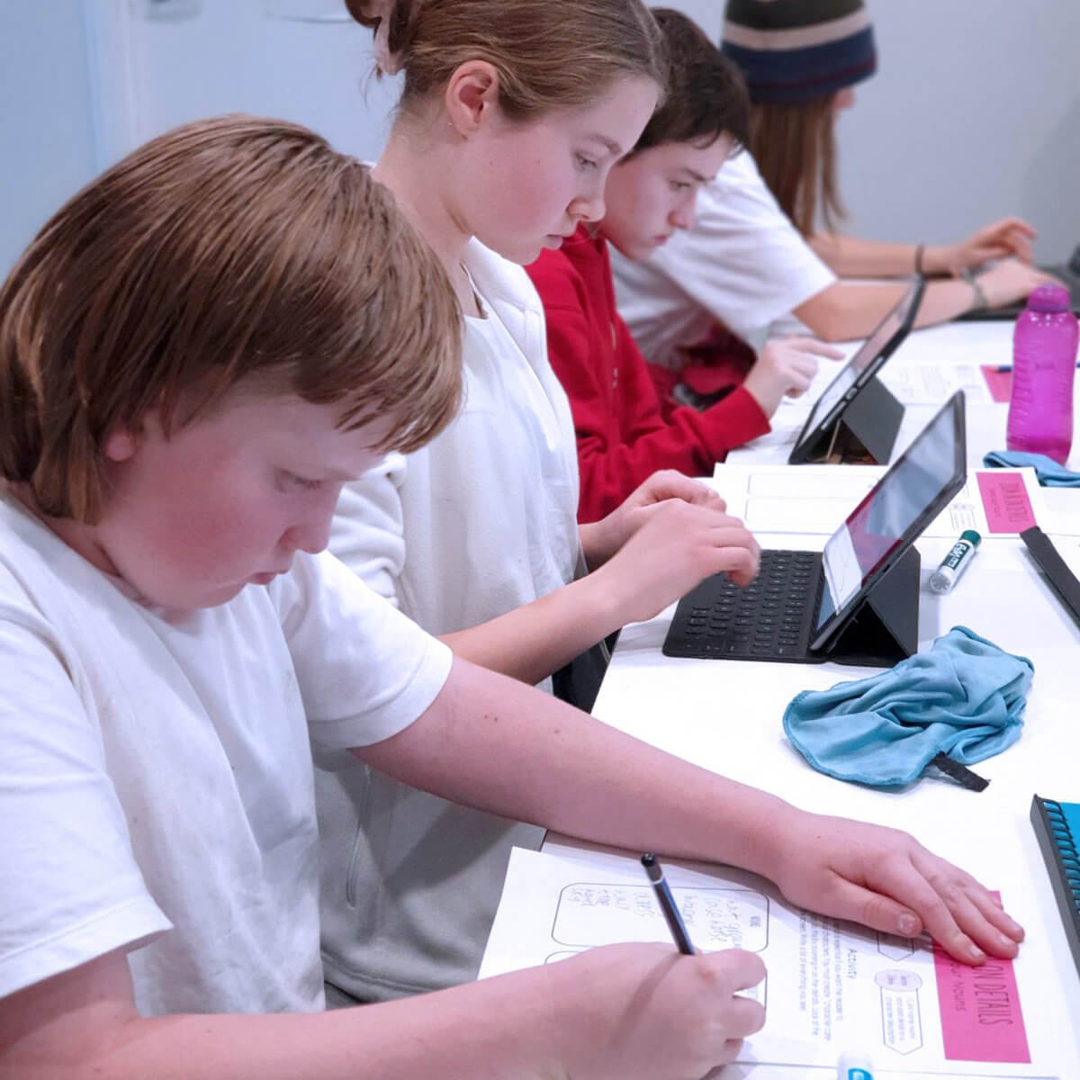 Students working on tablets and writing during a Positive Prep learning session.